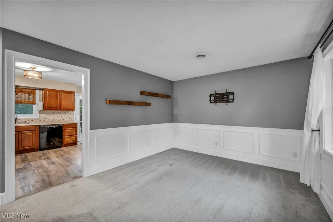 Carpeted empty room with a decorative wall and a wainscoted wall
