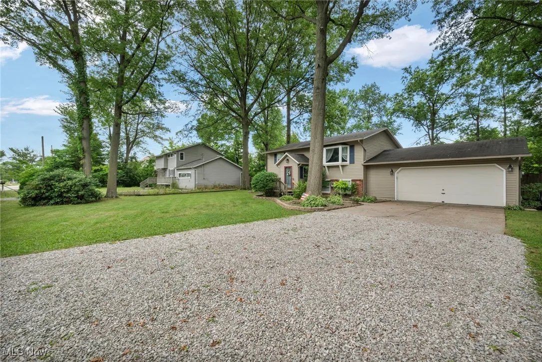 Bi-level home featuring driveway, a garage, a front yard, and brick siding