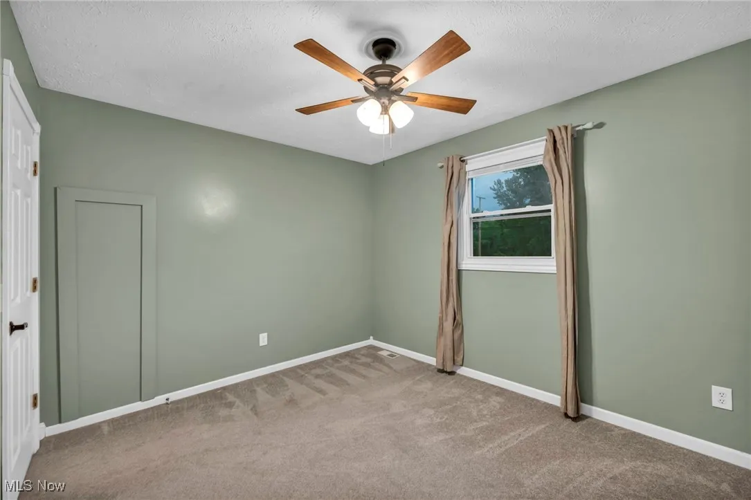 Unfurnished room featuring carpet flooring, ceiling fan, and a textured ceiling