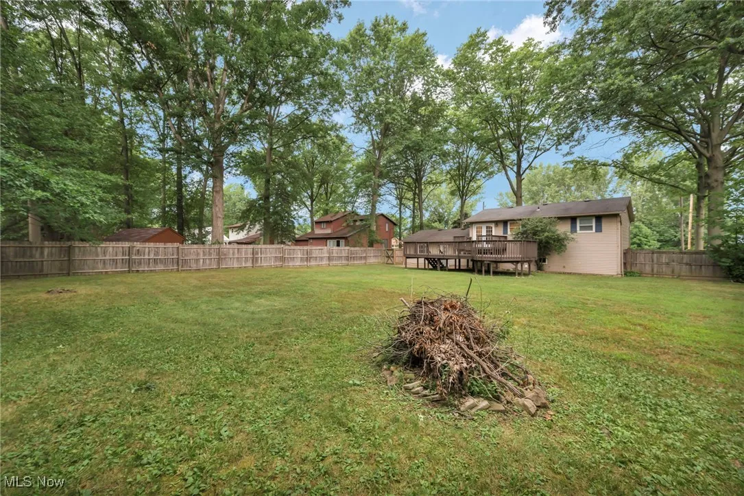 Fenced backyard featuring a wooden deck and view of scattered trees