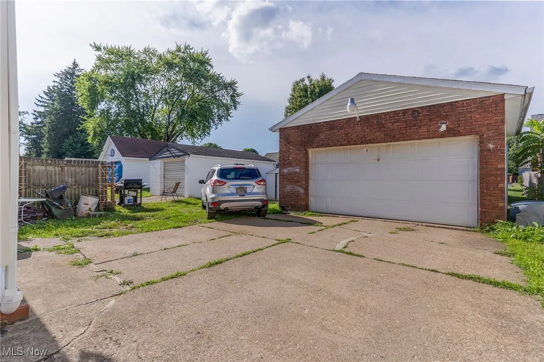 View of home's exterior with a garage, brick siding, an outdoor structure, and driveway
