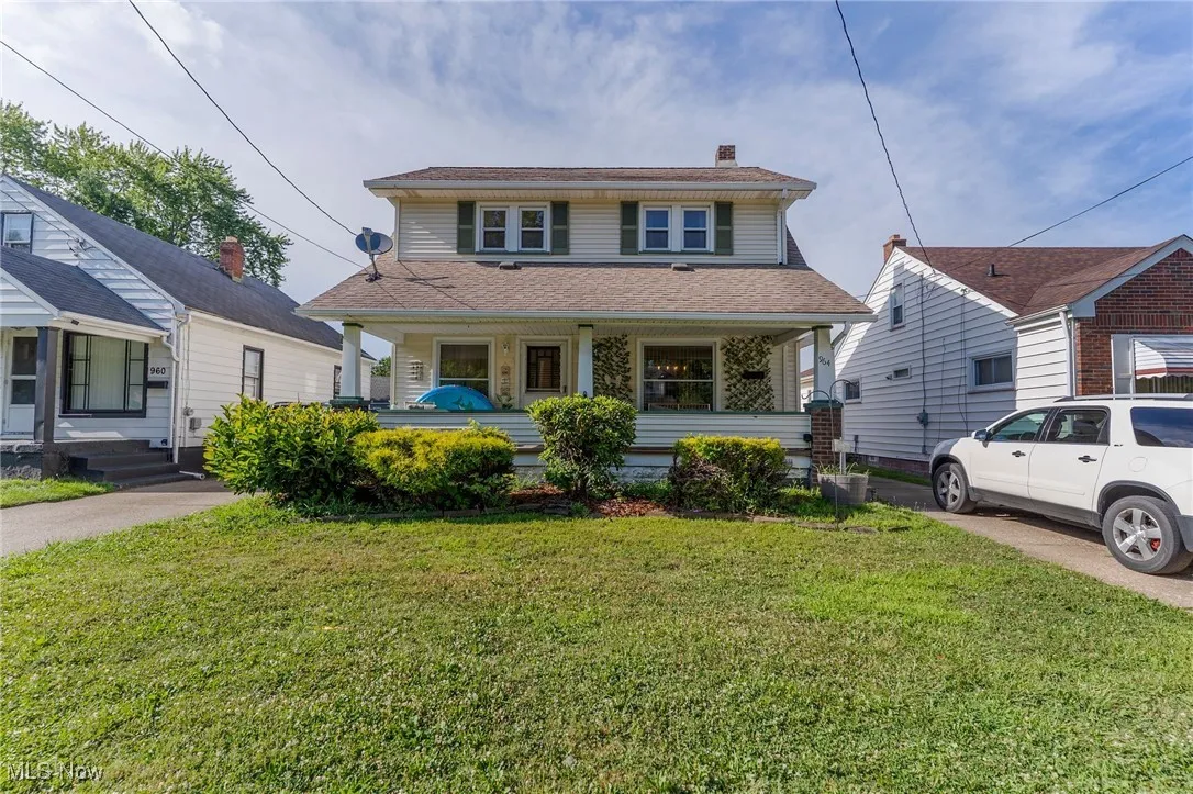View of front of home featuring a front lawn, roof with shingles, a chimney, and covered porch