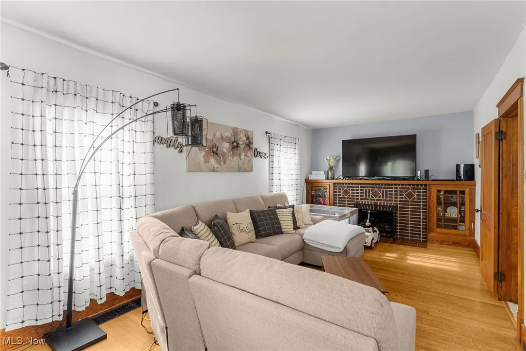 Living room featuring light wood-style flooring and a brick fireplace