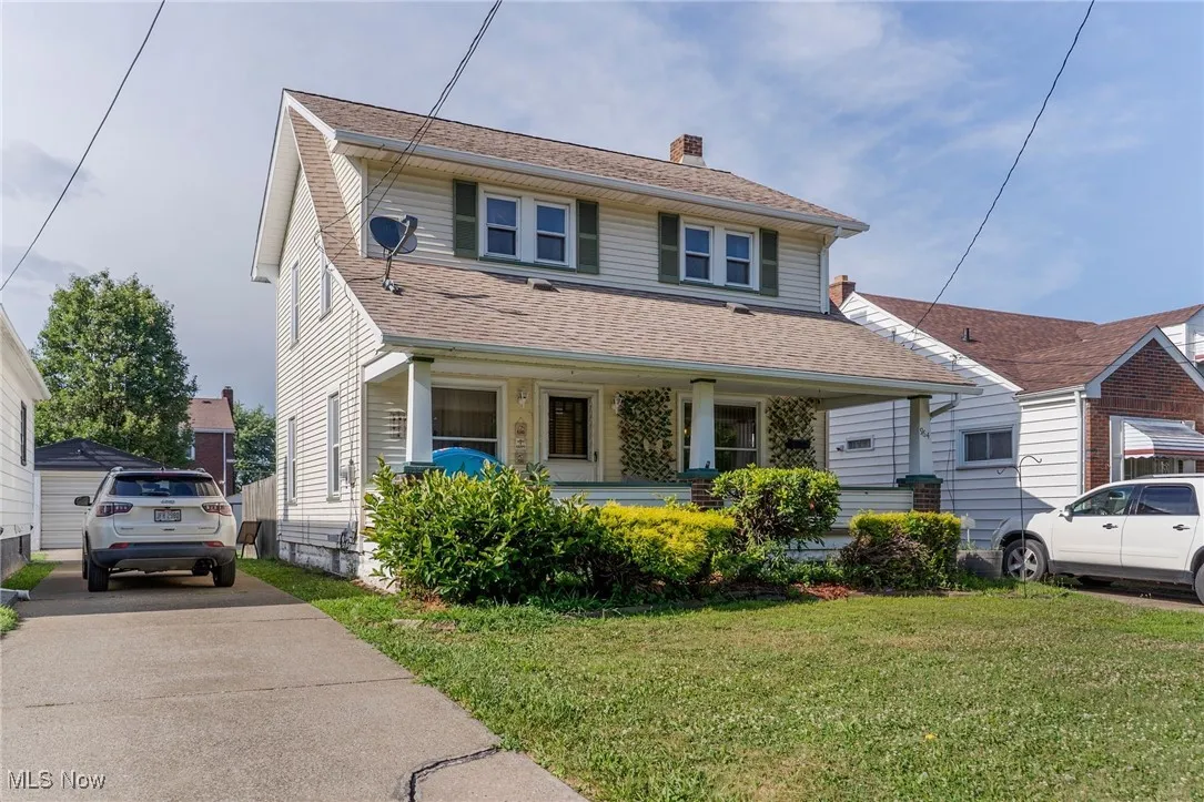 View of front of house with a front yard, a chimney, roof with shingles, and driveway