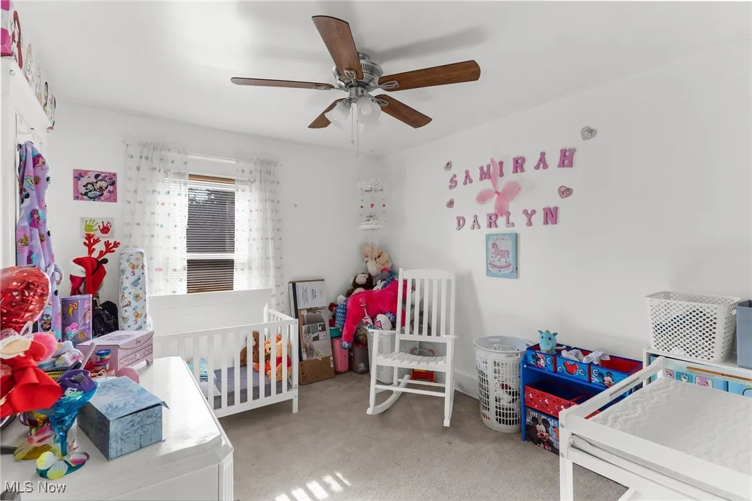 Carpeted bedroom with a ceiling fan