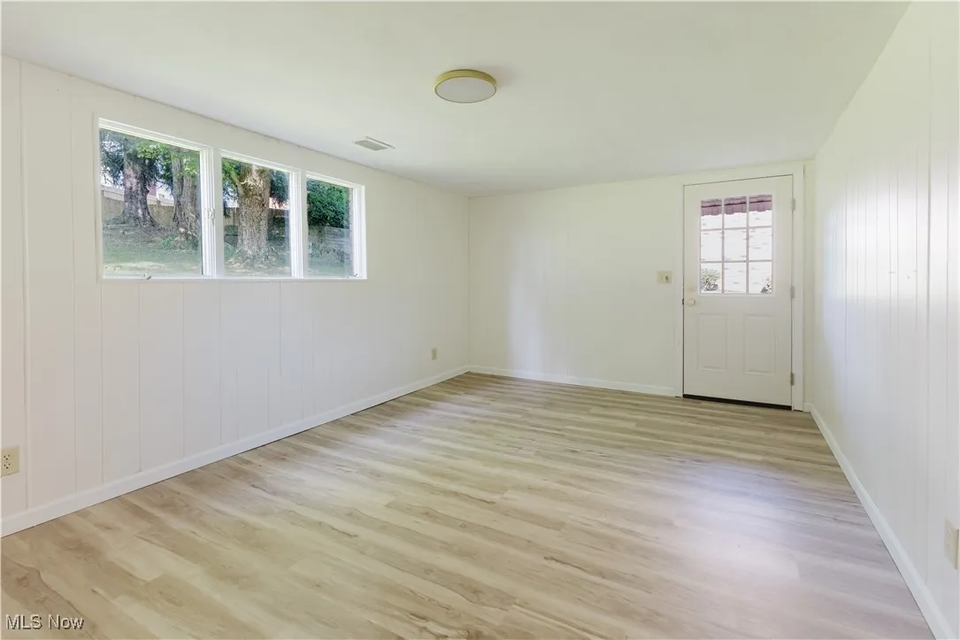 Empty room with light wood-style floors and wooden walls