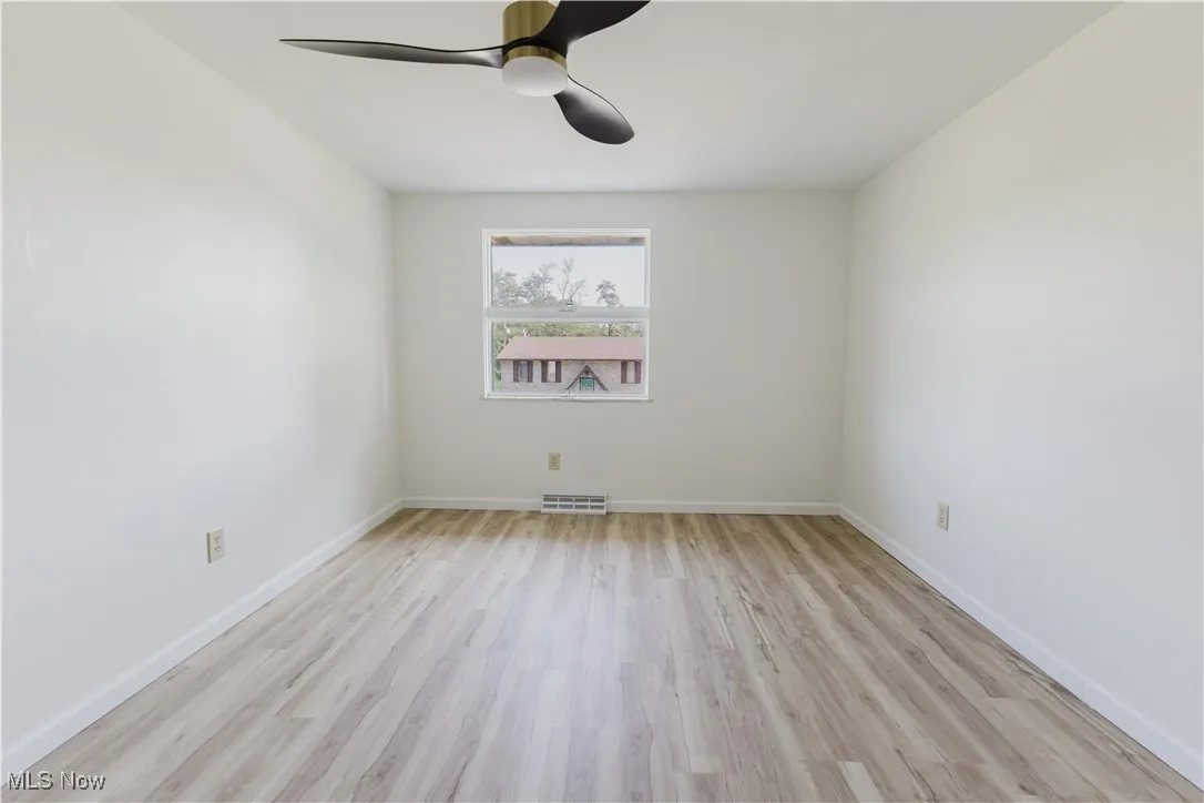 Empty room with light wood-style flooring and ceiling fan
