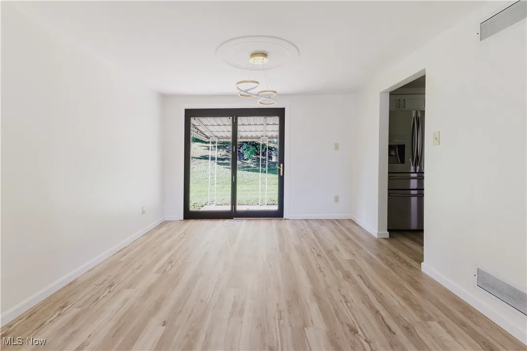 Empty room featuring light wood finished floors and a chandelier