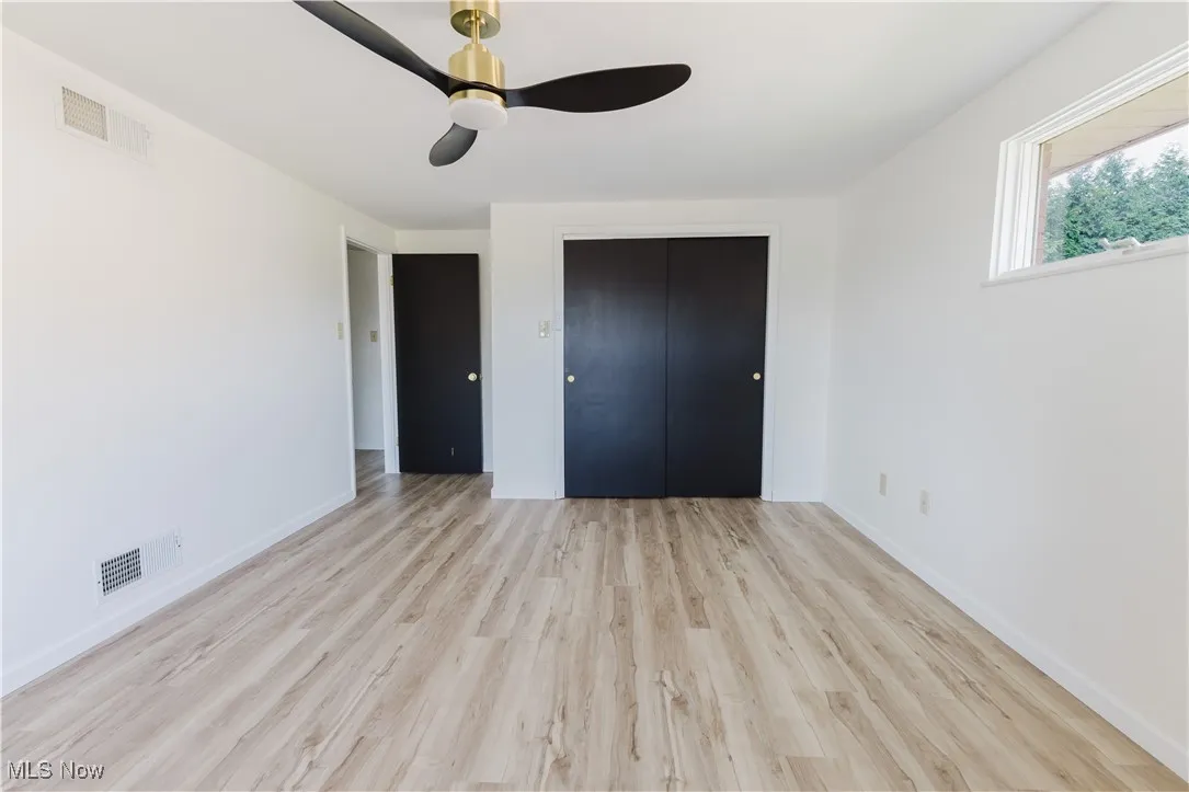 Unfurnished bedroom featuring wood finished floors, a closet, and a ceiling fan