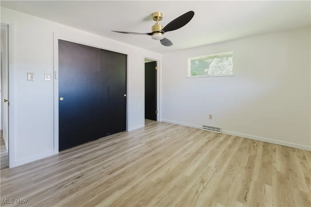 Unfurnished bedroom with light wood-style floors, a closet, and a ceiling fan