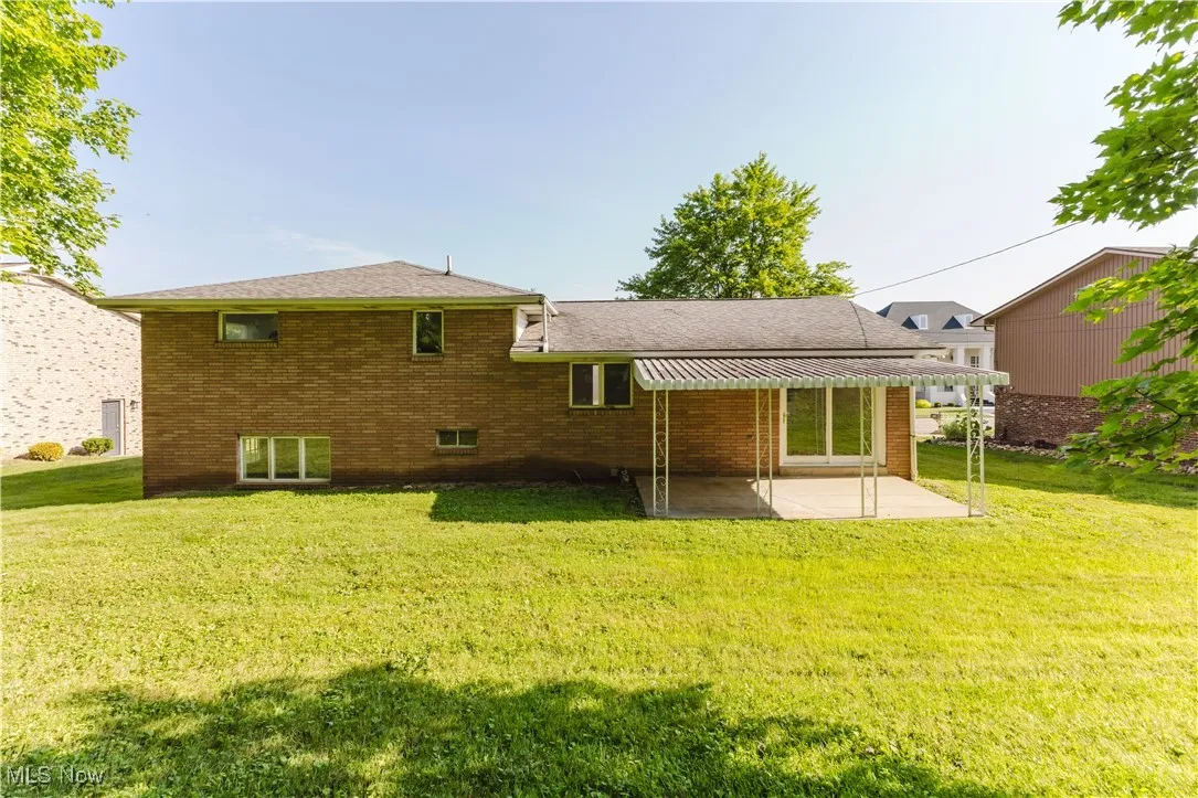 Back of house with a patio area, brick siding, and a yard