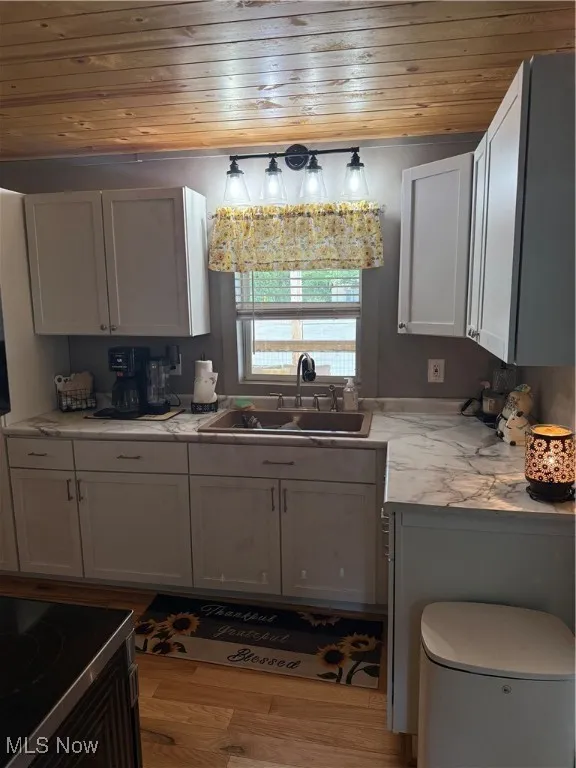 Kitchen with wooden ceiling, wood finished floors, and white cabinetry