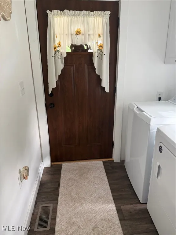 Laundry room with dark wood-style flooring and washing machine and clothes dryer