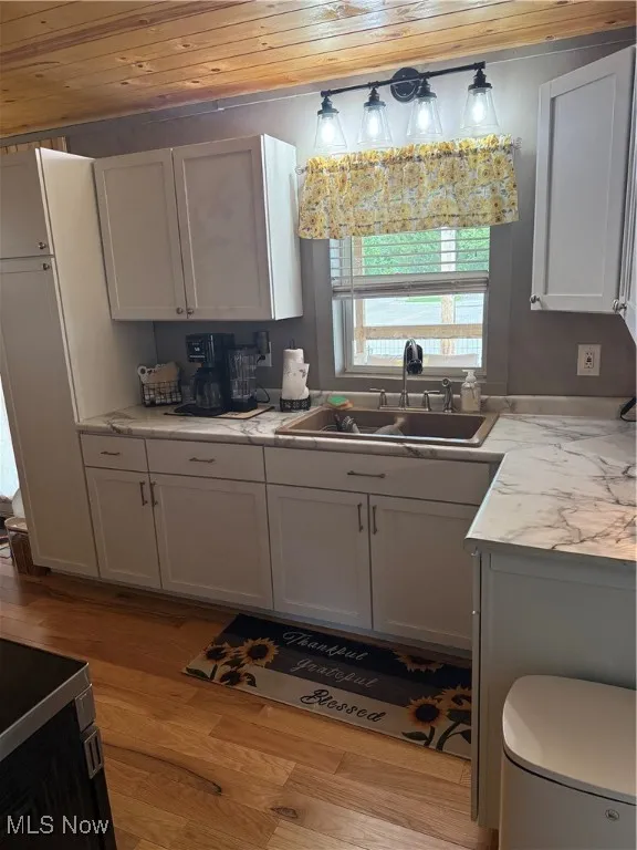 Kitchen with wood ceiling, light wood-type flooring, and white cabinets