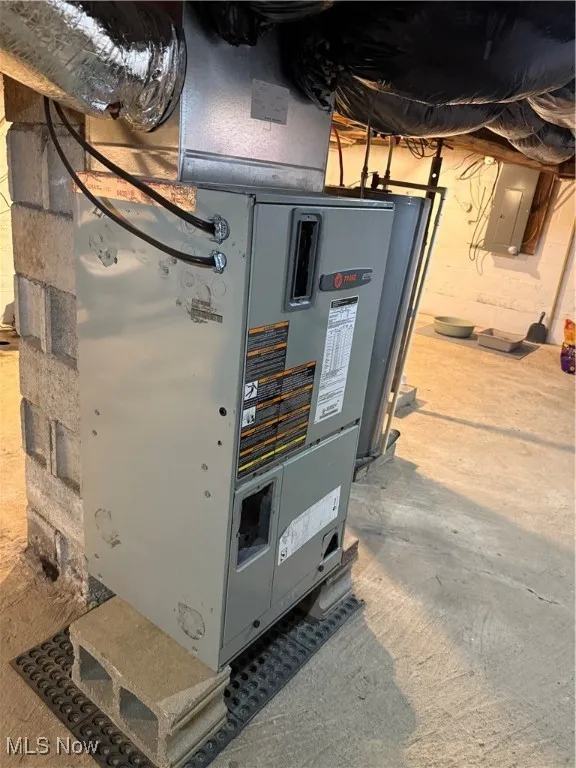 Utility room featuring water heater, electric panel, and heating unit