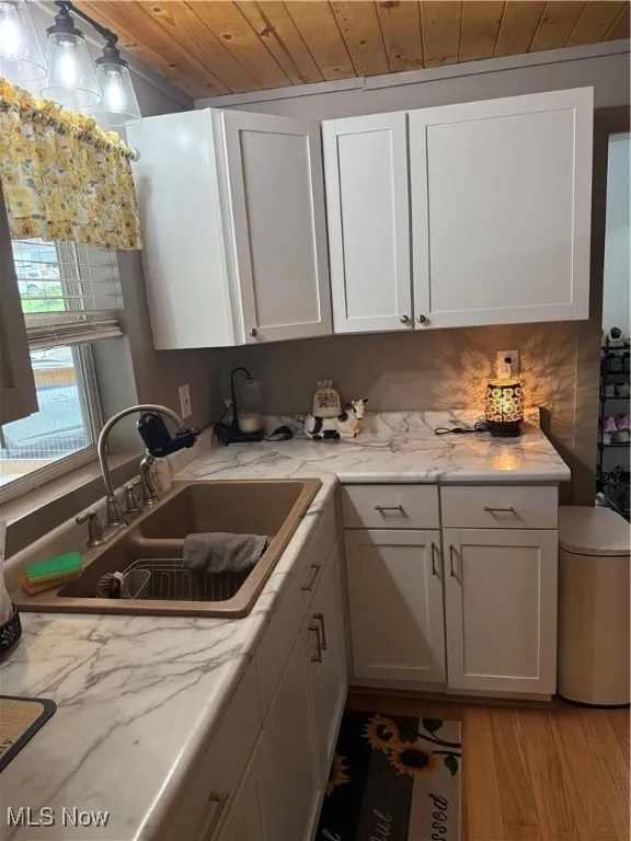 Kitchen featuring wooden ceiling, white cabinets, light stone countertops, and light wood finished floors