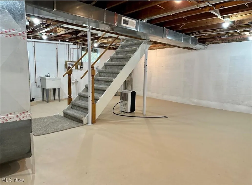 Unfinished below grade area featuring stairway and heating unit