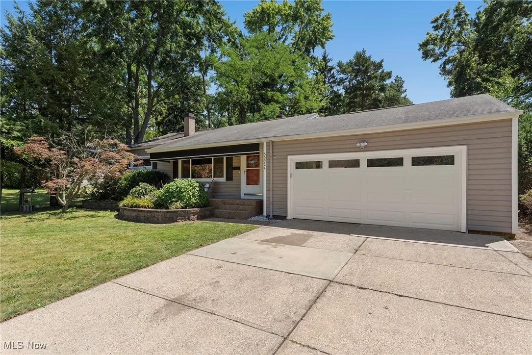 Ranch-style house with driveway, a front lawn, an attached garage, and a chimney