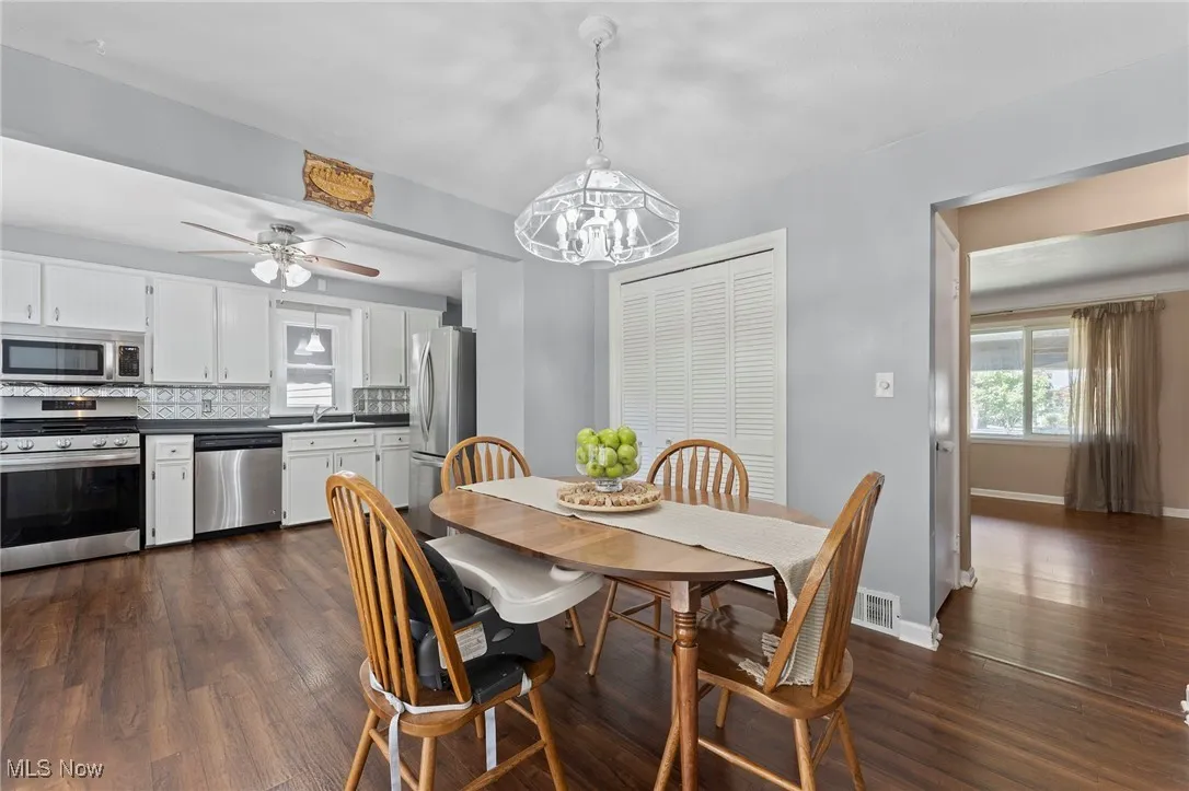 Dining area featuring dark wood like floors, a chandelier, and a ceiling fan