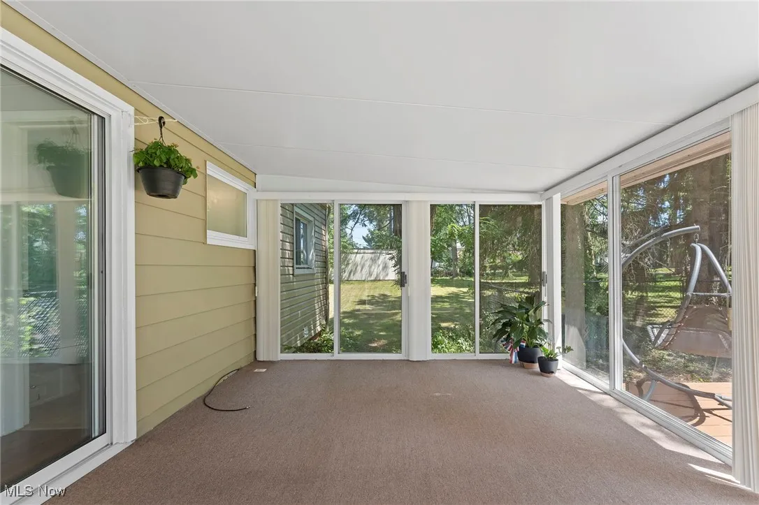Unfurnished sunroom featuring carpet and glass sliding doors