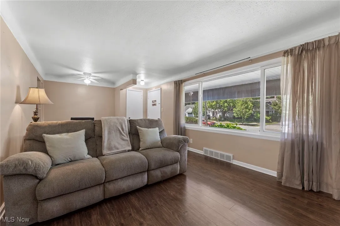 Living room featuring dark wood-type flooring, ceiling fan, and a textured ceiling