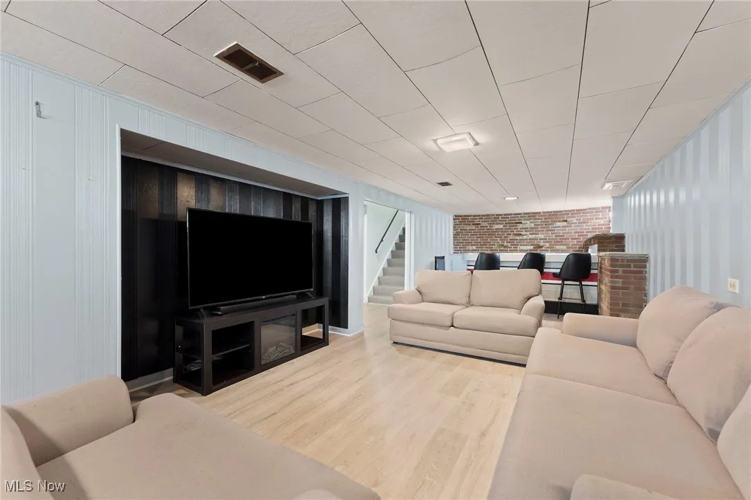 Basement with wood like floors, brick wall, and stairway