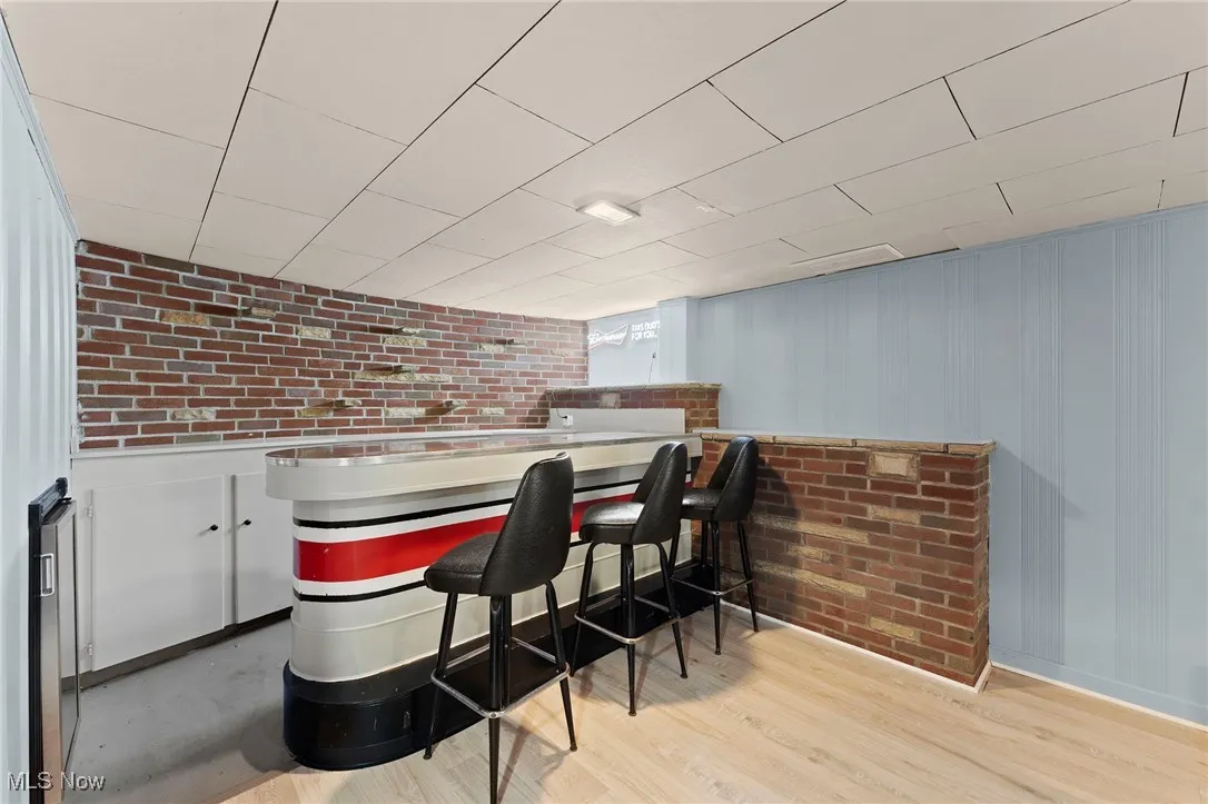 Indoor dry bar with wood like floors and brick wall