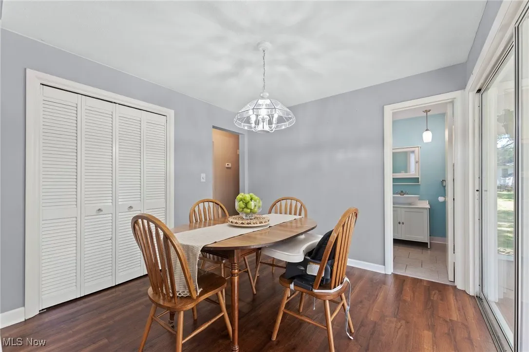 Dining space with a chandelier and dark wood like flooring