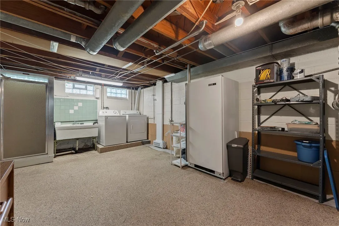 Basement featuring washing machine and clothes dryer and freestanding refrigerator