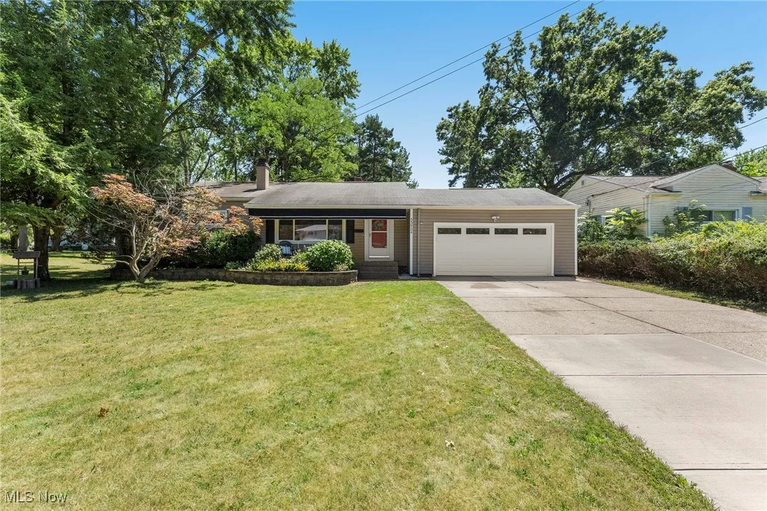 View of front of home featuring a chimney, driveway, an attached garage, and a front lawn