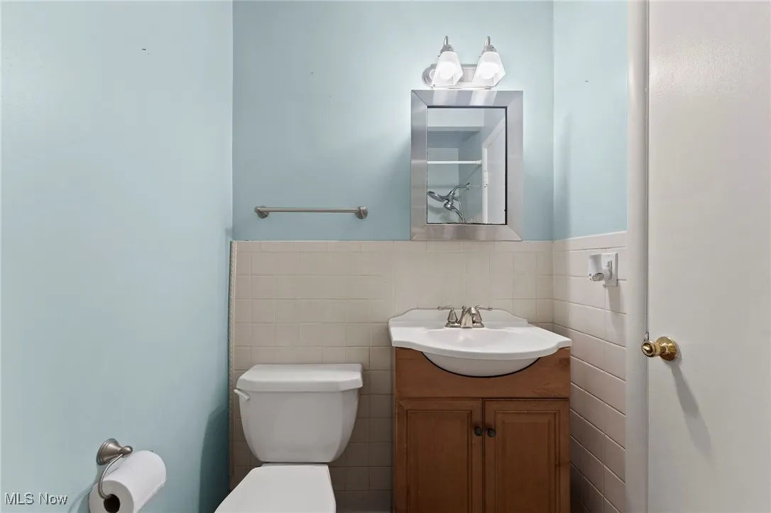 Bathroom with tile walls, vanity, and a wainscoted wall