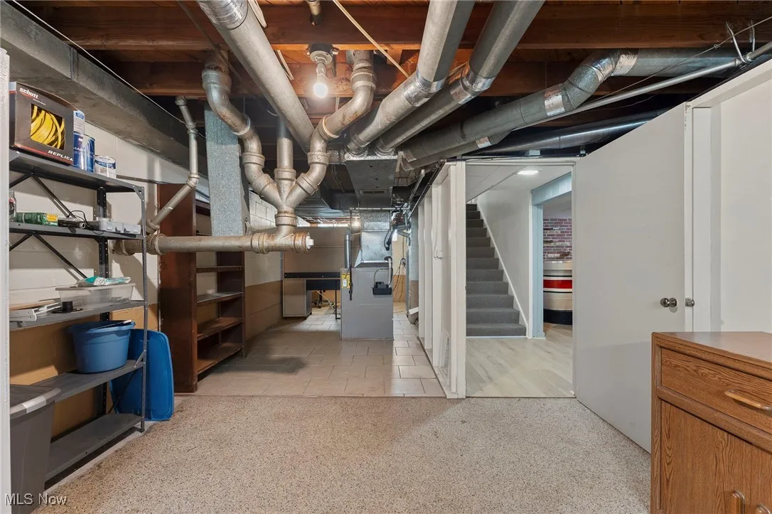 Unfinished basement with heating unit and stairs