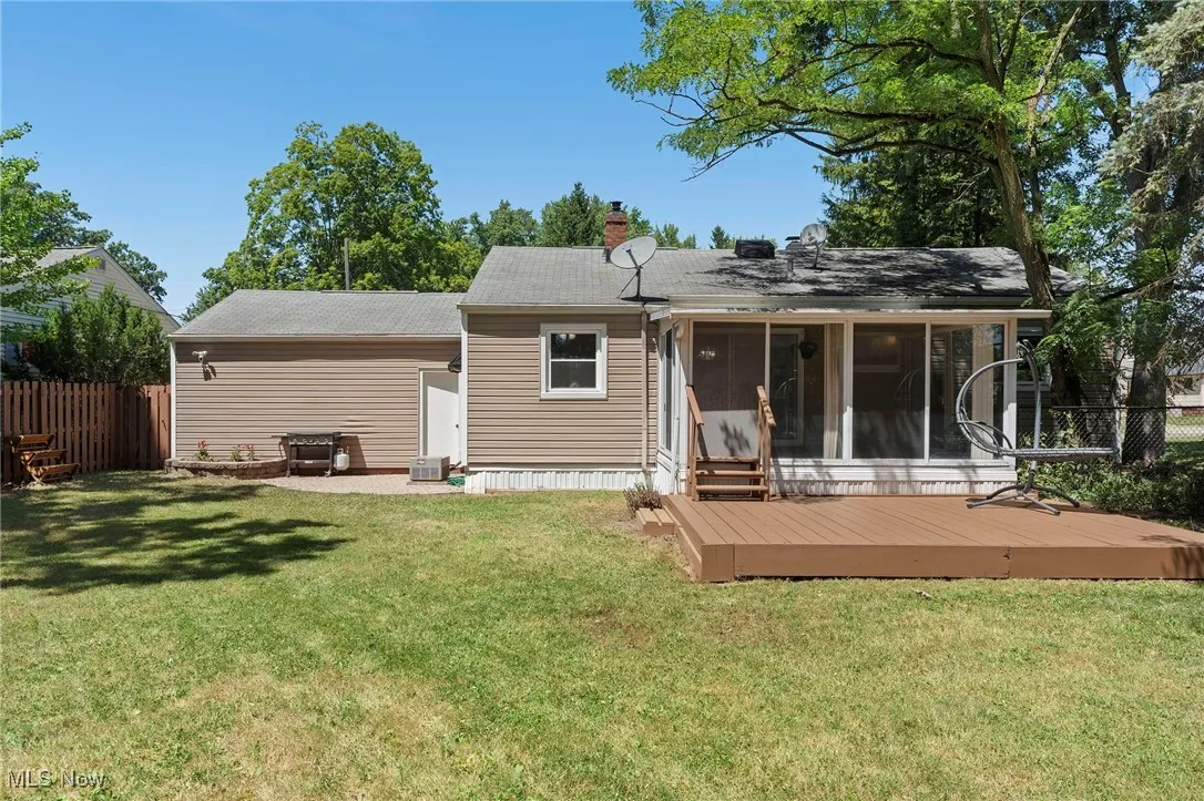 Rear view of property featuring a sunroom, a wooden deck, and a chimney