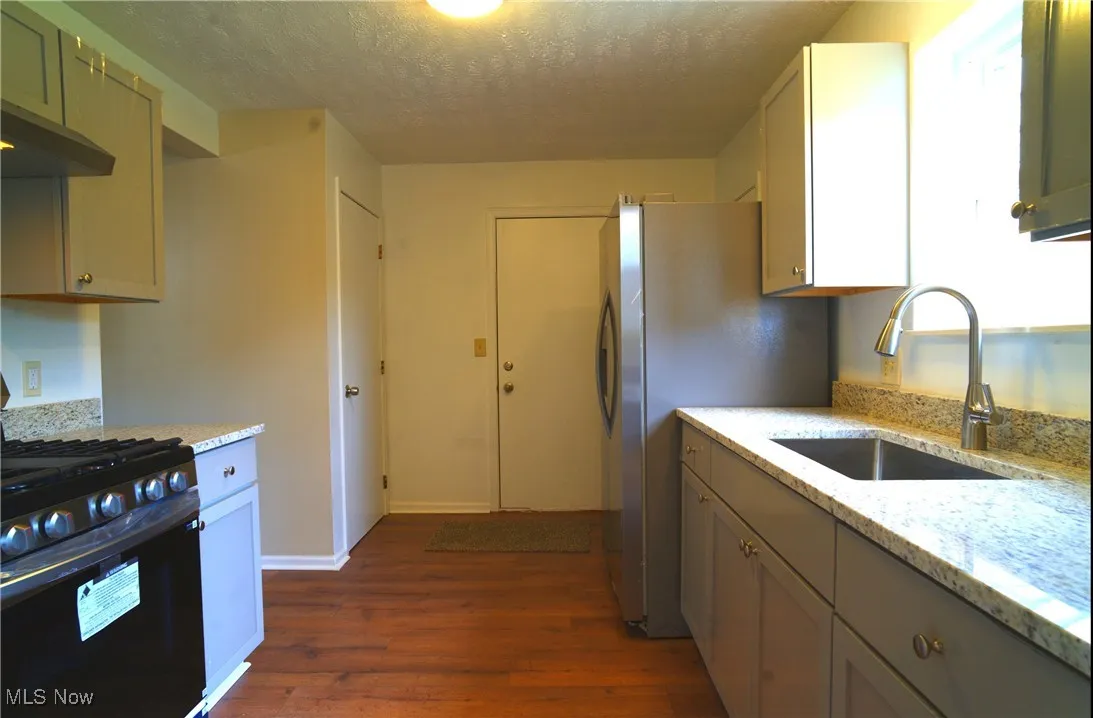 Kitchen featuring granite counters, gas range and refrigerator