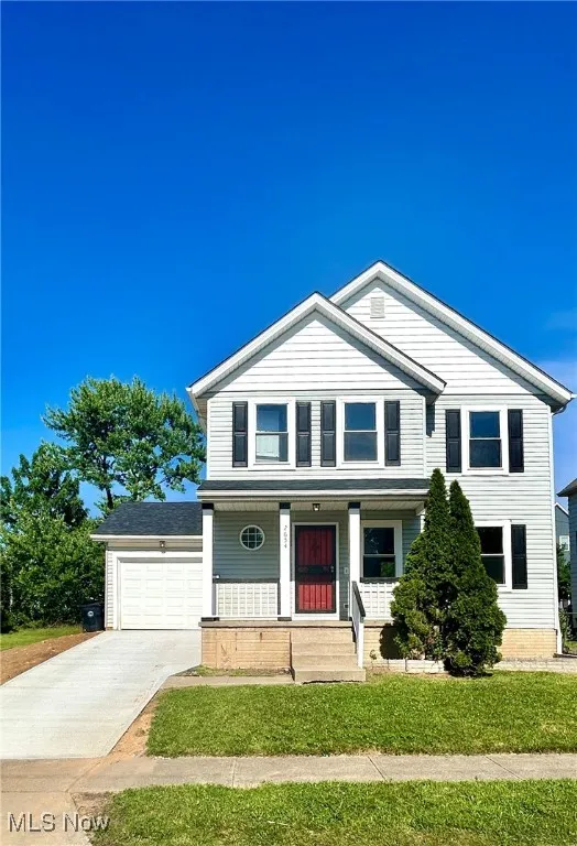 View of front of property with concrete driveway, a porch, and a garage