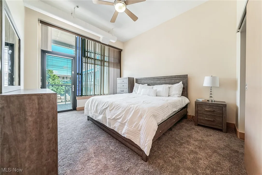 Carpeted bedroom featuring high ceiling, access to balcony, ceiling fan, walk-in closet, and private, full bathroom.