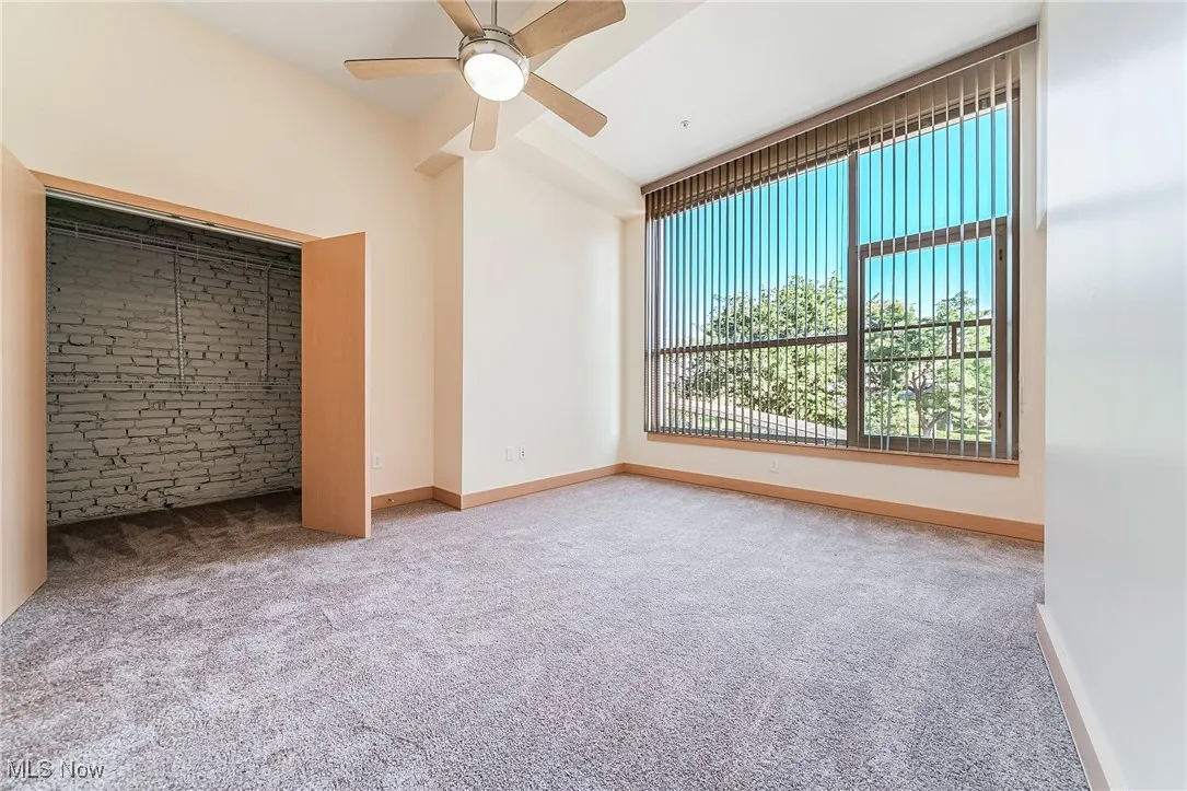 Unfurnished bedroom featuring carpet, walk-in closet, and a ceiling fan.