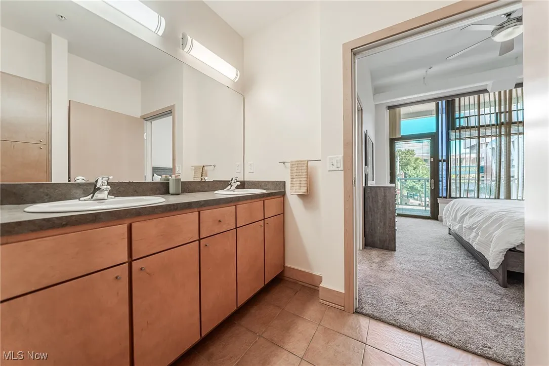 Ensuite bathroom with tile flooring, double vanity, and storage, and walk-in shower.
