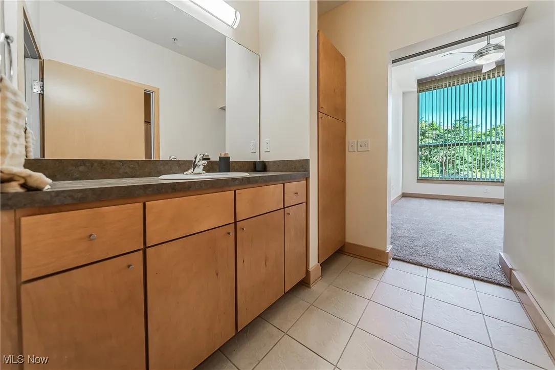 Bathroom featuring tile flooring, vanity, storage, tub and shower.