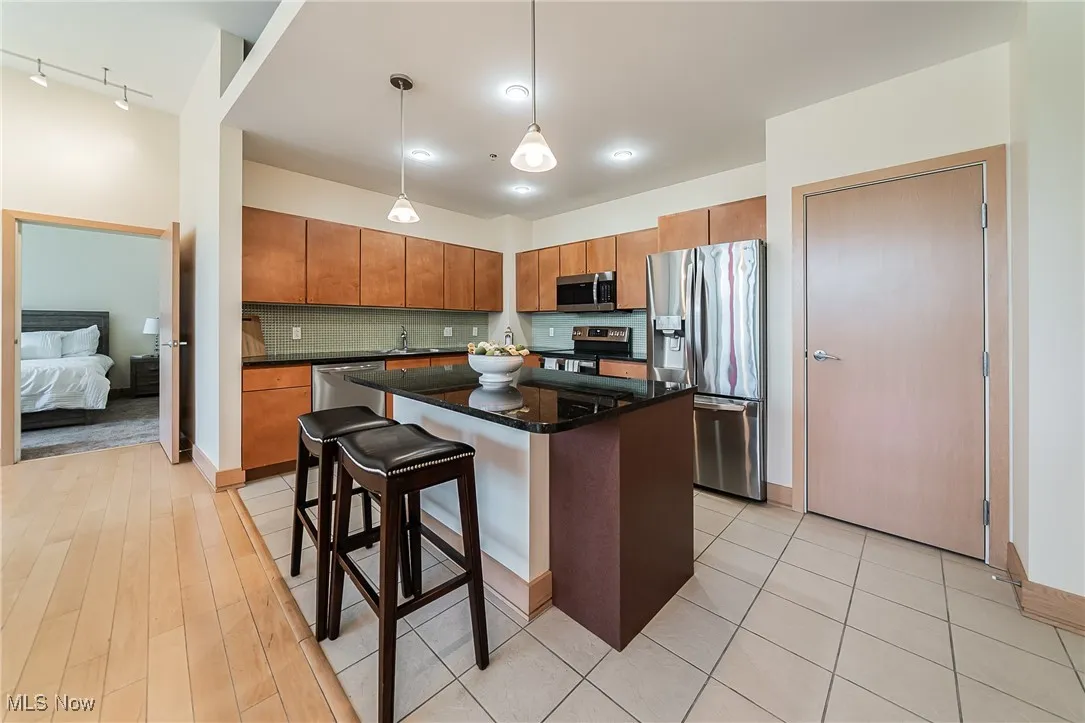 Kitchen with pendant lighting, stainless steel appliances, a center island, and pantry.