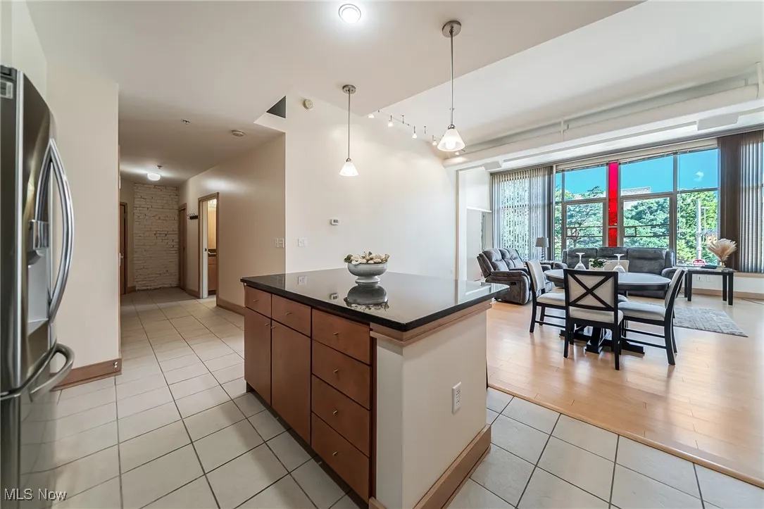 Kitchen featuring dark countertops, light tile patterned flooring, stainless steel fridge with ice dispenser, a center island, and open floor plan