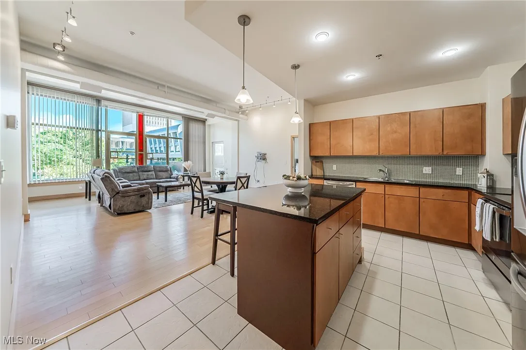 Kitchen with tasteful backsplash, pendant lighting, light tile patterned flooring, open floor plan, and a kitchen island
