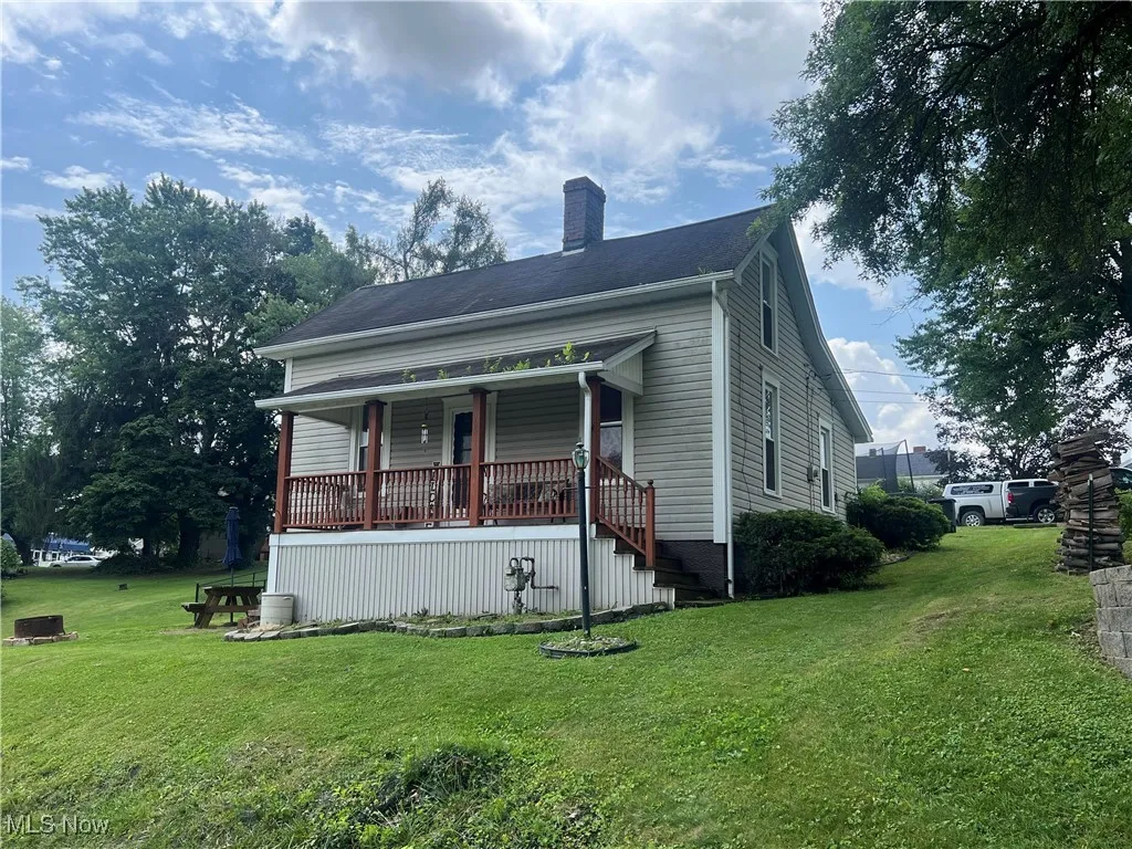 View of front of house with a porch, a front lawn, a chimney, and a shingled roof