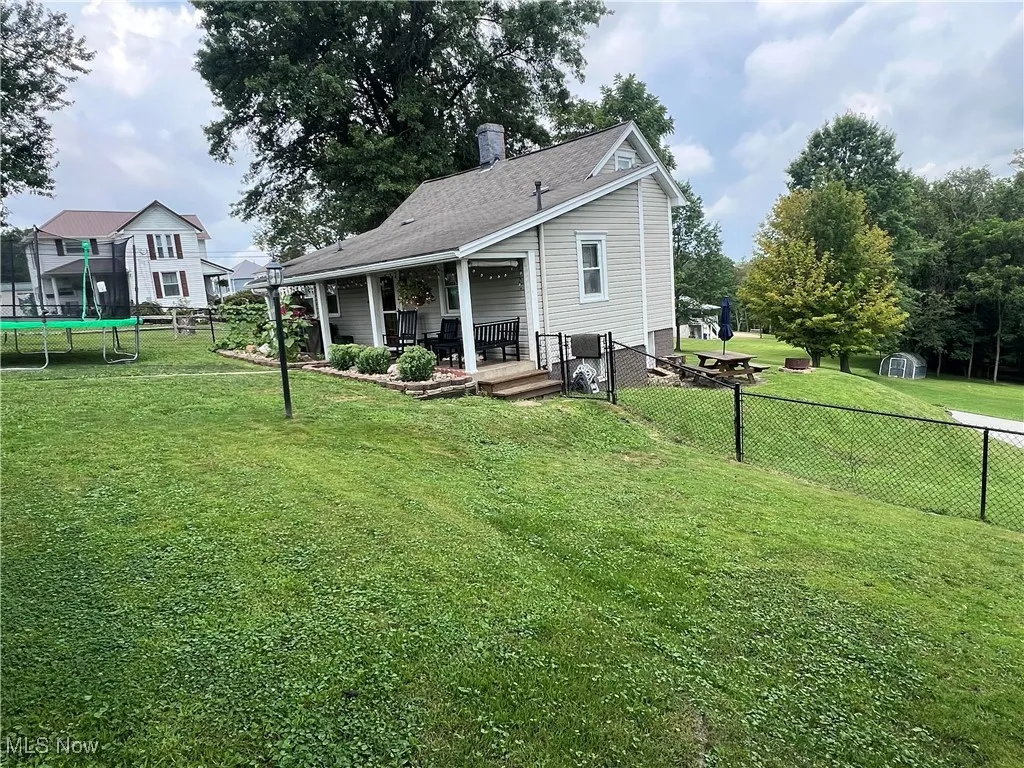 Rear view of house with a trampoline, a fenced backyard, and a chimney