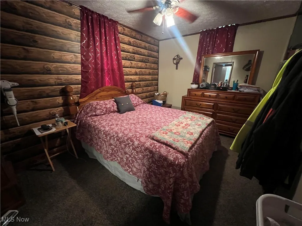 Bedroom featuring a textured ceiling, carpet flooring, and ceiling fan
