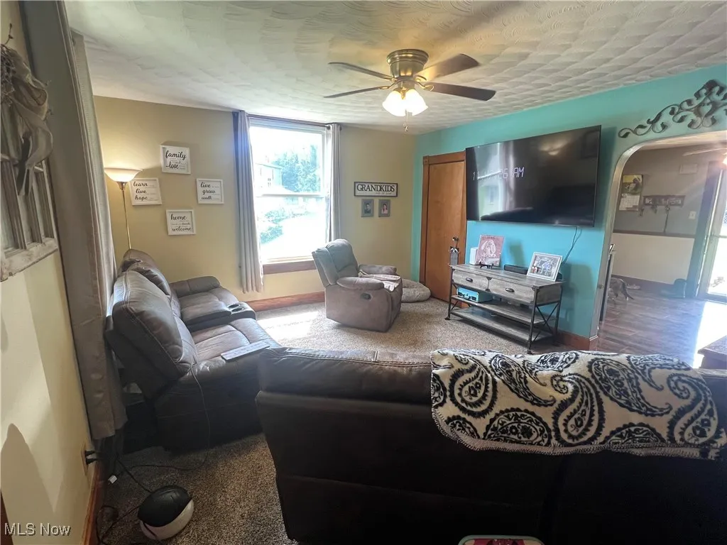Living room featuring a ceiling fan and a textured ceiling