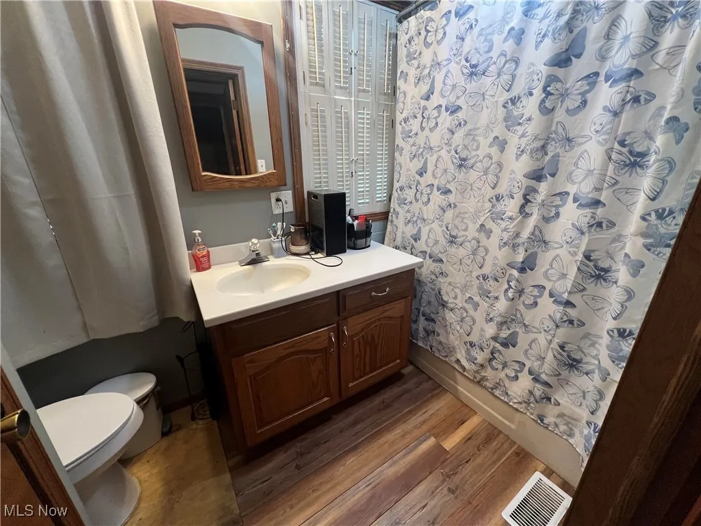 Full bath with wood finished floors, vanity, and shower / bath combination with curtain