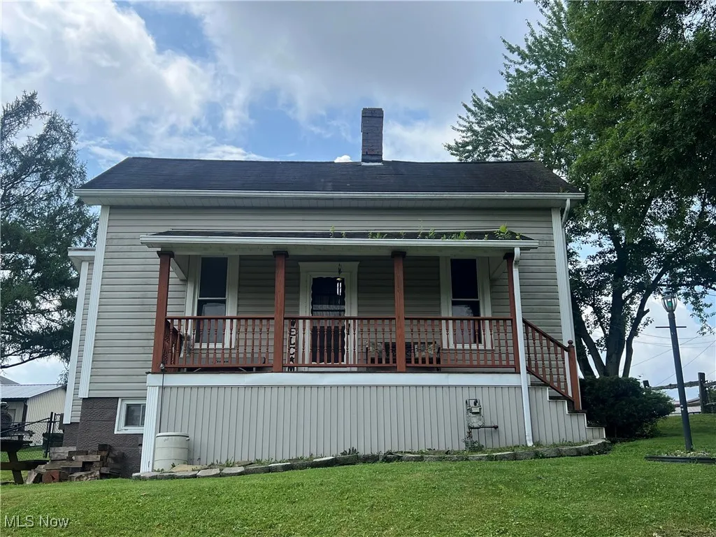 View of front of house with a chimney, covered porch, and a front yard
