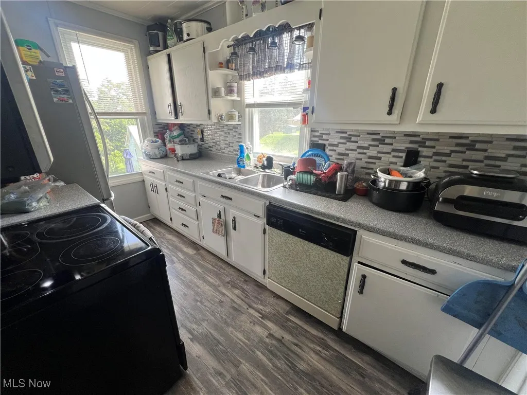 Kitchen with black electric range, plenty of natural light, dishwasher, tasteful backsplash, and ornamental molding