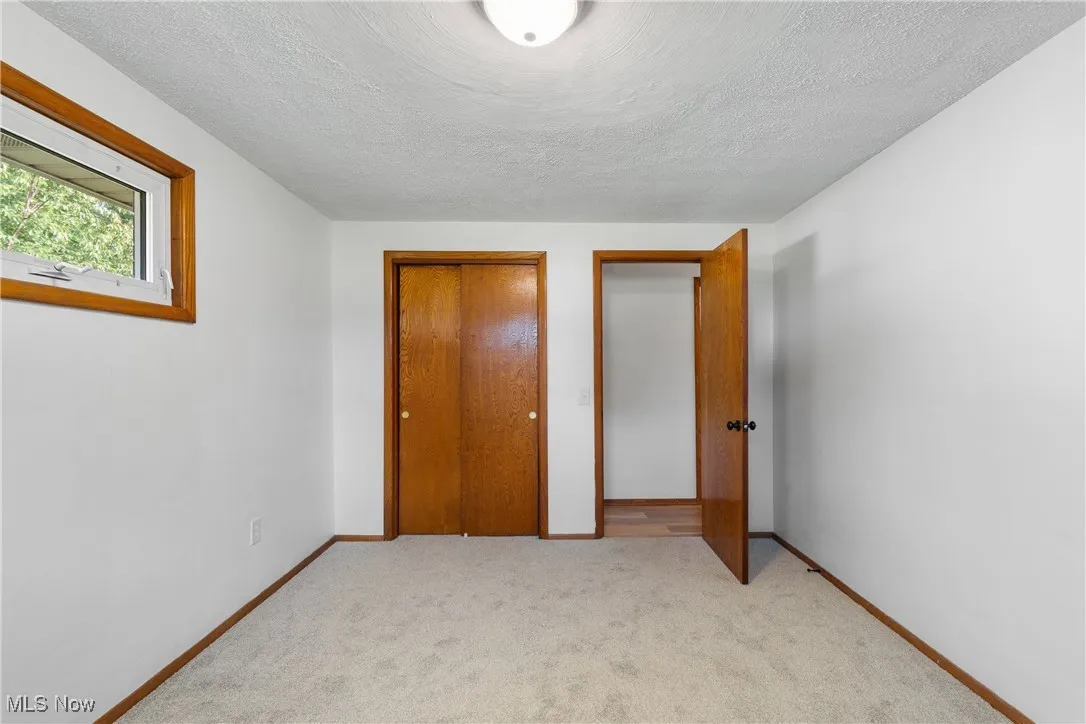 Unfurnished bedroom featuring a textured ceiling and light carpet